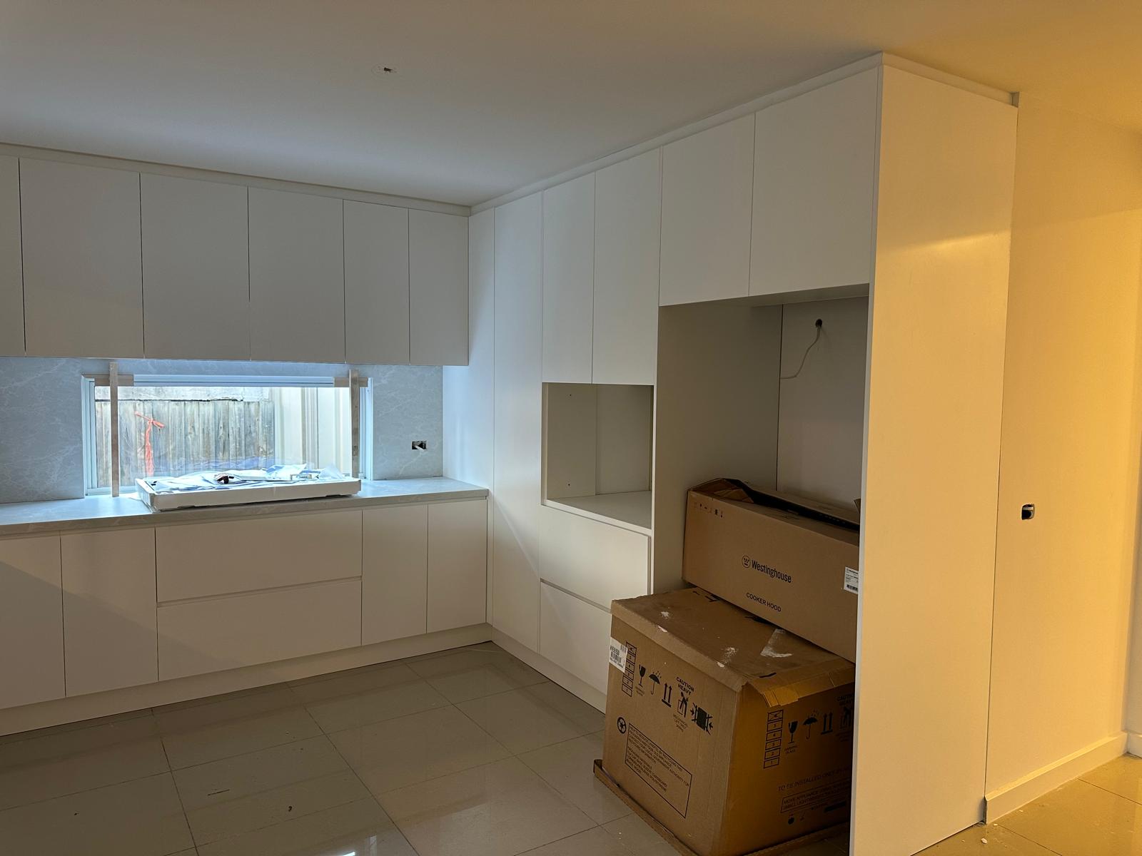 Floor-to-ceiling white kitchen cabinetry with window feature.